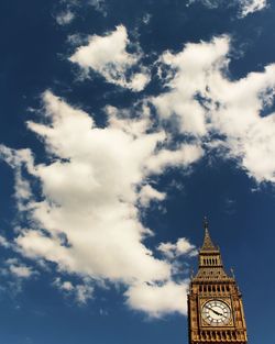 High section of clock tower against blue sky and clouds