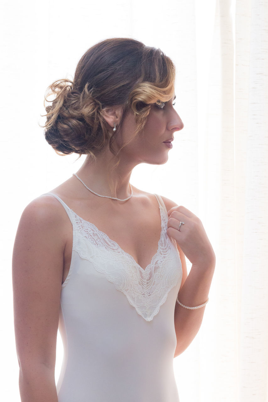 MIDSECTION OF WOMAN LOOKING AWAY AGAINST WALL