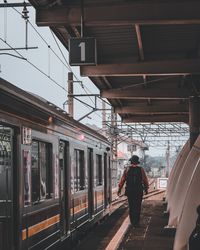 Rear view of man walking on railroad station platform