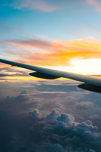 Airplane flying over cloudscape during sunset