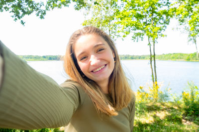 Portrait of smiling young woman against trees