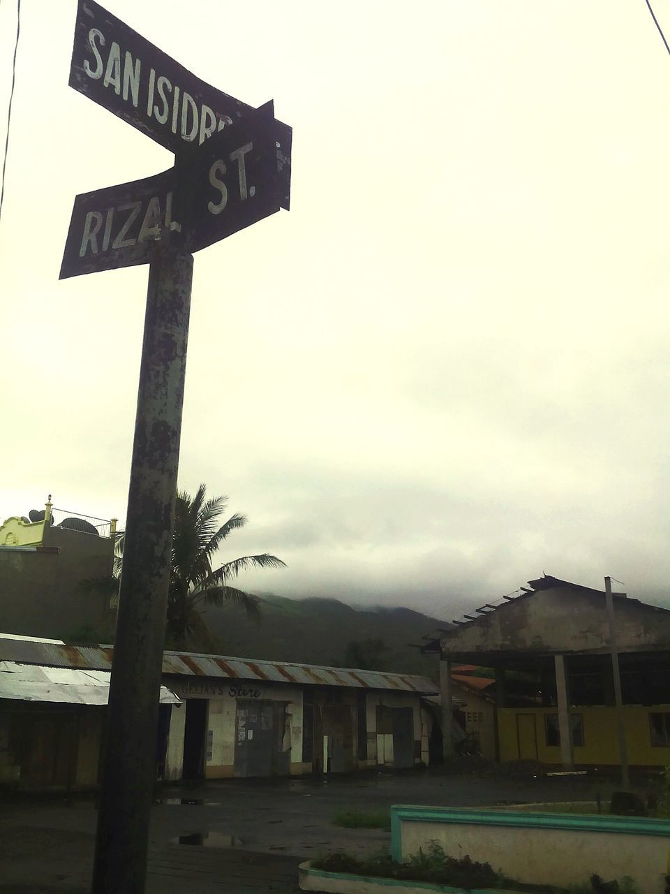 text, built structure, building exterior, architecture, communication, sky, western script, road sign, guidance, sign, information sign, low angle view, weather, information, house, outdoors, cloud - sky, directional sign, no people, day