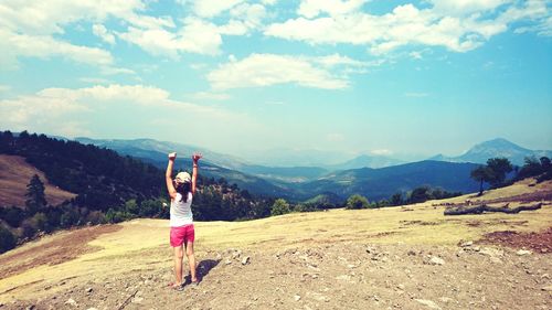 Full length of young woman photographing on mountain against sky