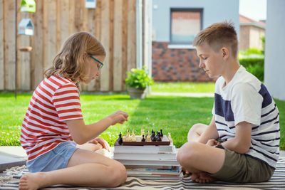 Rear view of boy sitting on boys playing outdoors