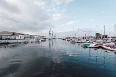 Boats moored at harbor against sky