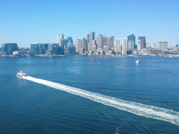 High angle view of boat moving on river by city against clear sky