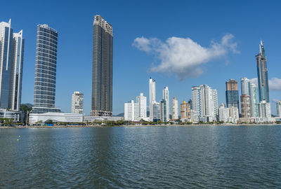 Sea by modern buildings against sky in city