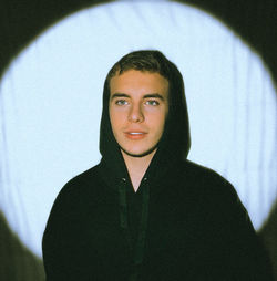 Portrait of young man standing against wall