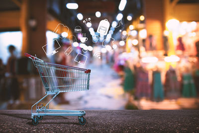 Digital composite image of icons emerging from shopping cart at clothing store