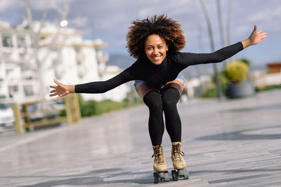 Portrait of smiling young woman roller skating on street in city