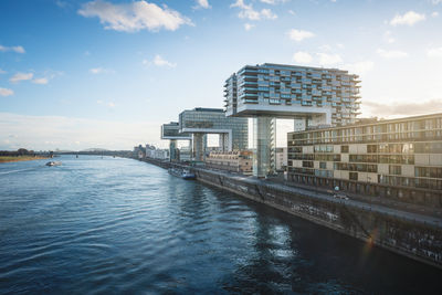 Buildings by river against sky