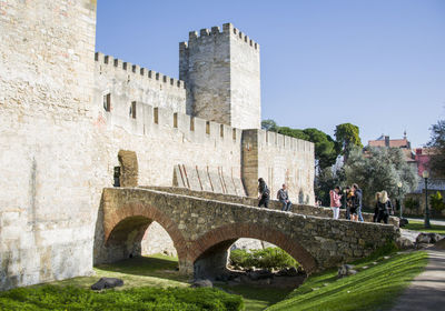 Tourists at old ruin building against sky