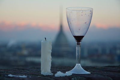 Close-up of wine glass and candle against sunrise in turin