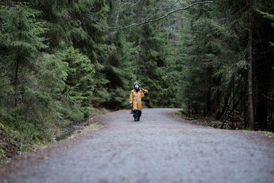 Young boy walking through a tall forest playing and singing to himself