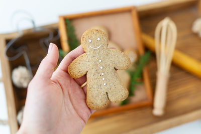 A woman's hand holds a gingerbread man. cooking gingerbread at home lies on a wooden tray. 