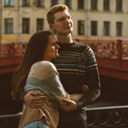 Young couple embracing while standing outdoors