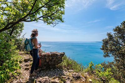 Woman standing by sea against sky