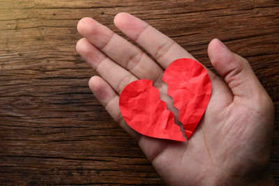 Close-up of hand holding heart shape on wood