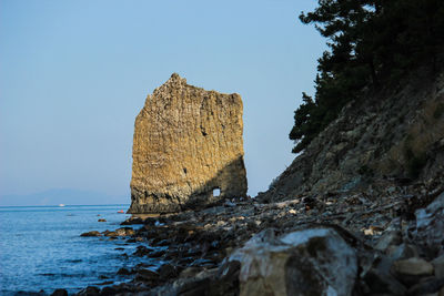 Rock formations in sea against clear blue sky