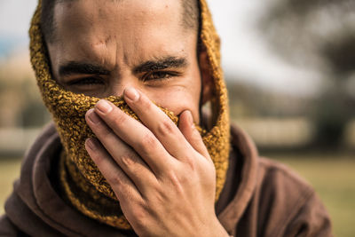 Close-up portrait of man covering face standing outdoors