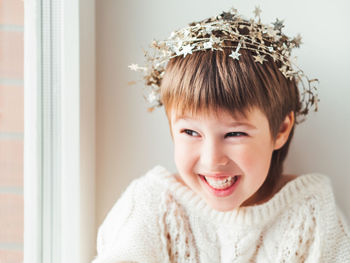 Laughing kid with decorative star tinsel for christmas tree. boy in cable-knit oversized sweater. 