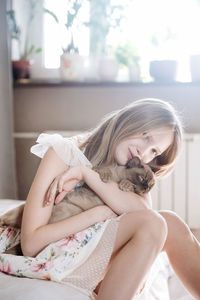 Portrait of blondie girl with burmese cat at home