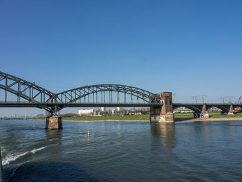 Bridge over river against clear blue sky