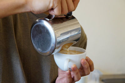 Barista having latte art coffee in white mug.