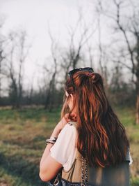 Young woman standing against tree