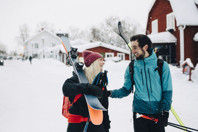 Cheerful male and female friends looking at each other during winter