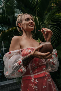 Portrait of young woman standing against trees