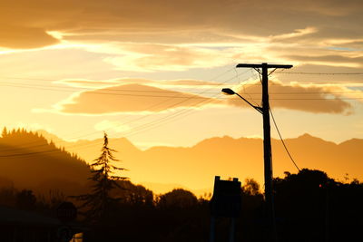 Silhouette electricity pylon against sky during sunset