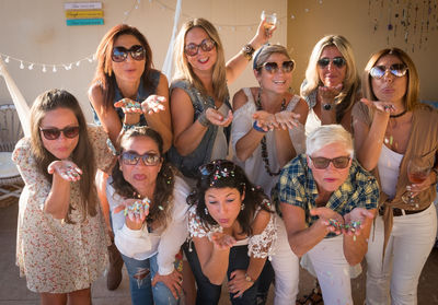 Female friends blowing confetti during party