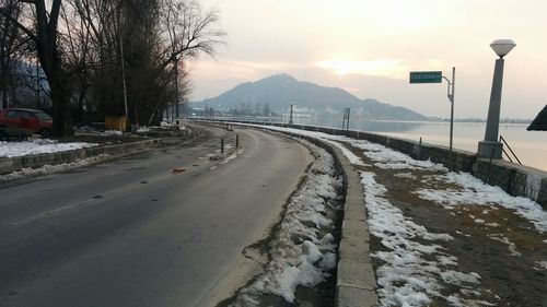 Snow covered road by mountain against sky