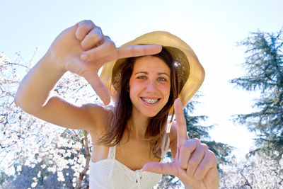 Portrait of young woman wearing hat against sky