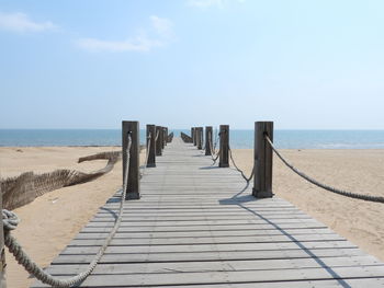 Wooden posts on beach against sky