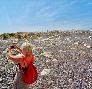 Woman photographing through mobile phone while standing on landscape