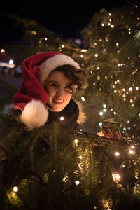 Happy young woman with gift by illuminated christmas tree at night