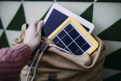 Woman putting a tablet into a backpack with a solar panel charger