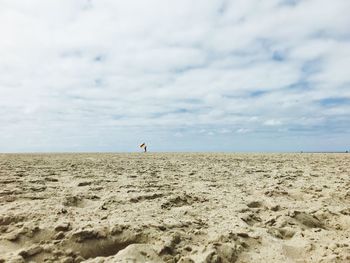 Scenic view of beach against cloudy sky