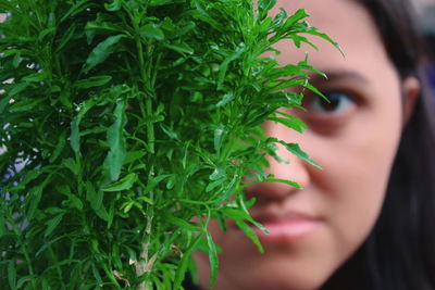 Close-up portrait of young woman with green plant