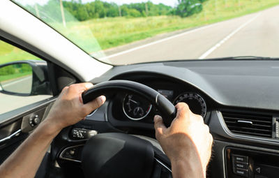 A male driver drives a car on the road, hands on the steering wheel. travel concept, commuting. 