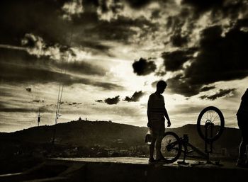 People on mountain against cloudy sky
