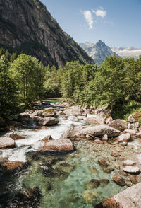 Stream flowing through rocks against sky