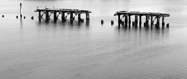 Wooden posts in sea against sky