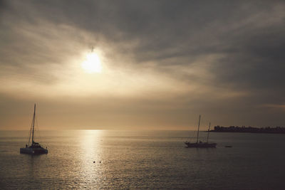 Sailboat sailing on sea against sky during sunset