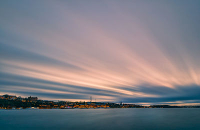 Illuminated city at waterfront during sunset