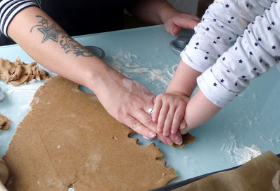 Cropped hands of mother and daughter preparing cookie in kitchen at home