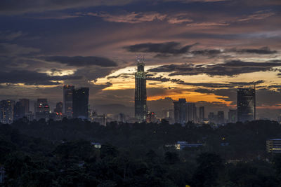 Illuminated buildings in city against sky during sunset