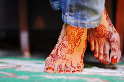 Low section of woman with henna tattoo on floor